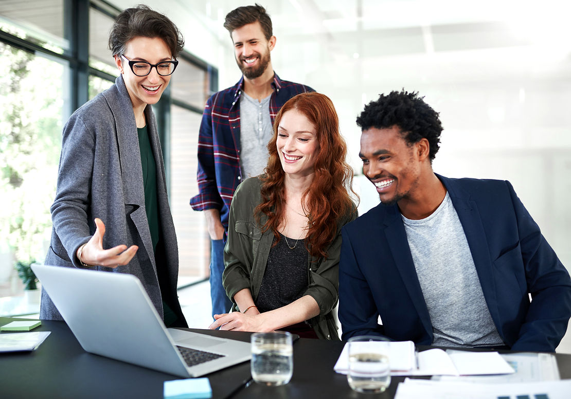 Group of coworkers looking at a computer smiling