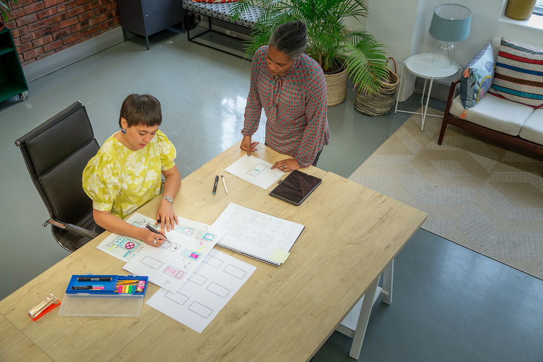 Two people working at a table with papers spread out