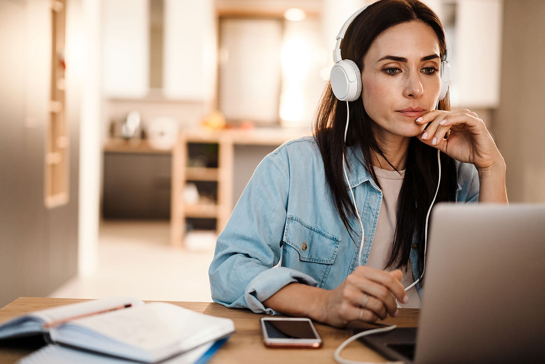 Woman working on laptop with headphones on