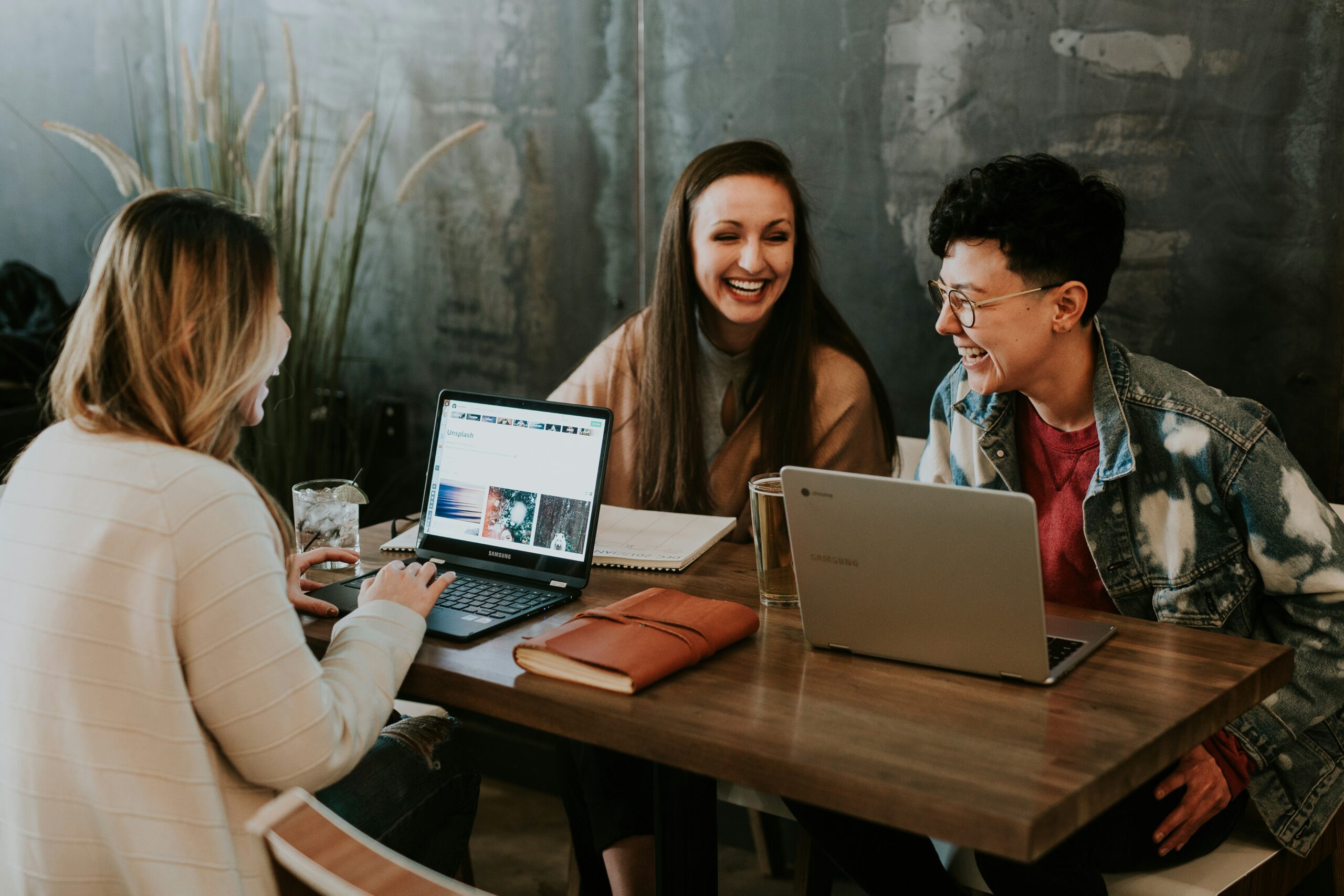 Coworkers sitting around a table with computers laughing