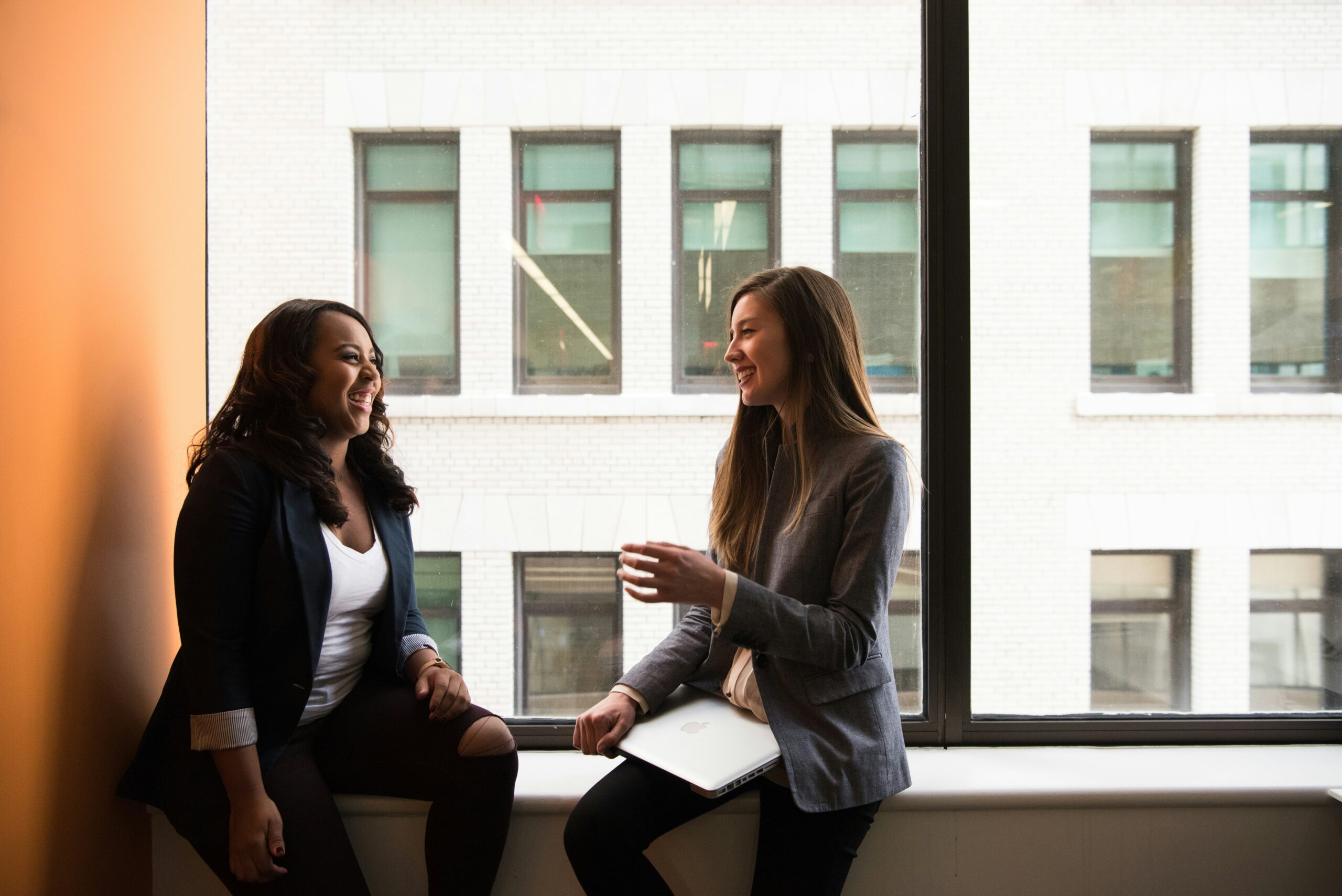 Two women sitting in windowsill talking