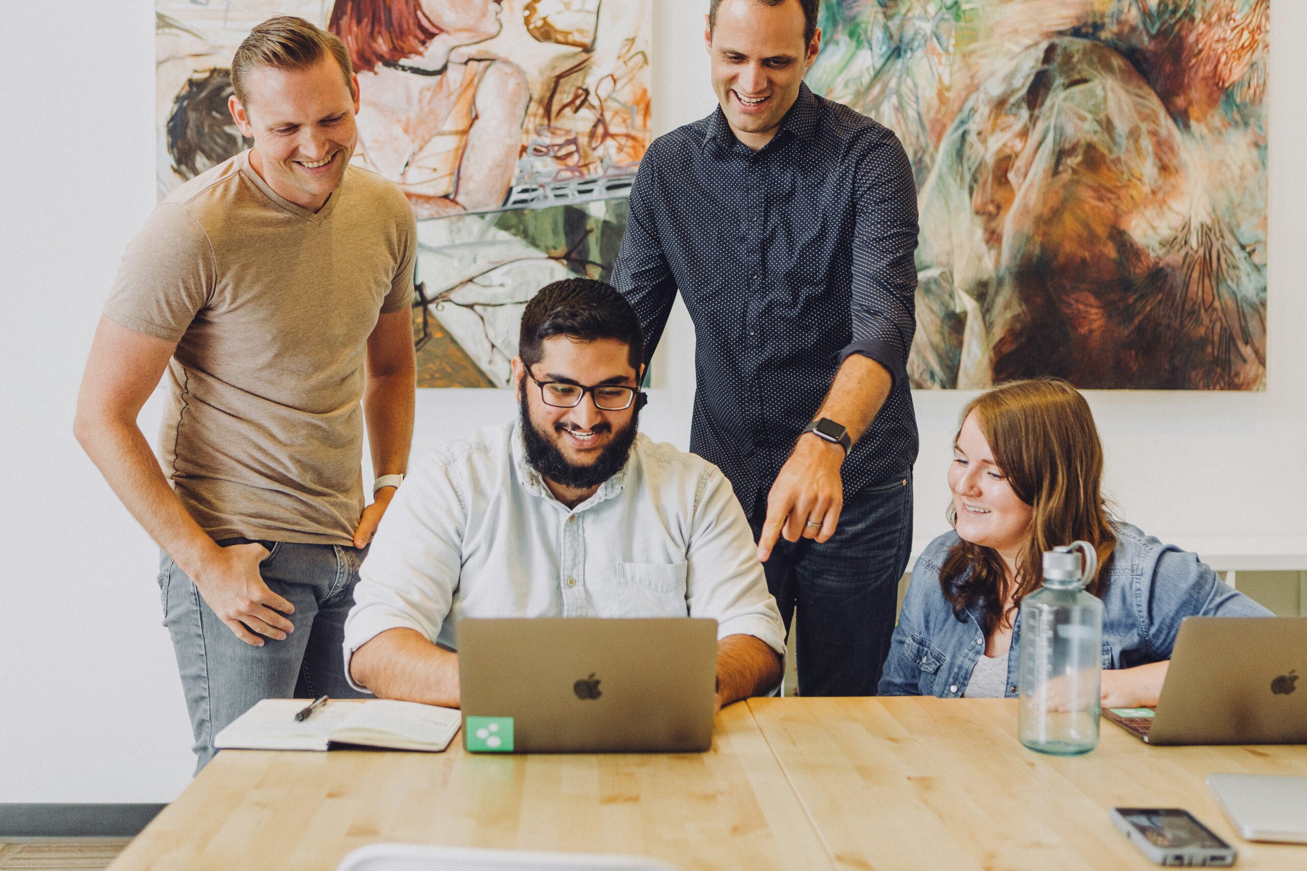 Four coworkers looking at a computer together